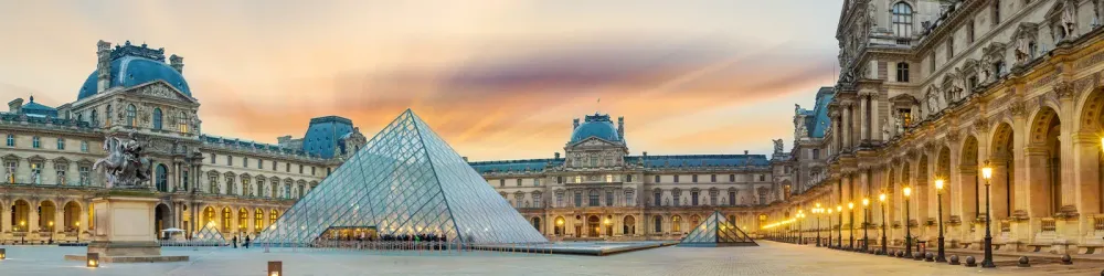 View of famous Louvre Museum with Louvre Pyramid at evening at sunset in Paris France